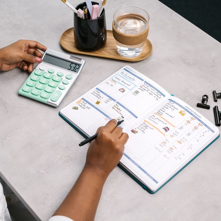 Hands working through a travel budget with a calculator and notebook
