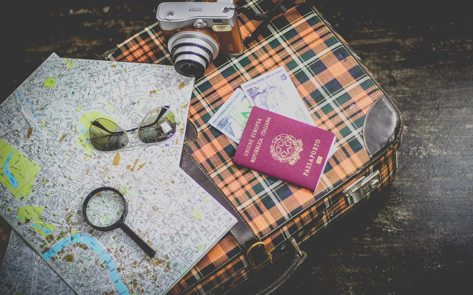 Passport, maps, and travel essentials laid out on a vintage suitcase